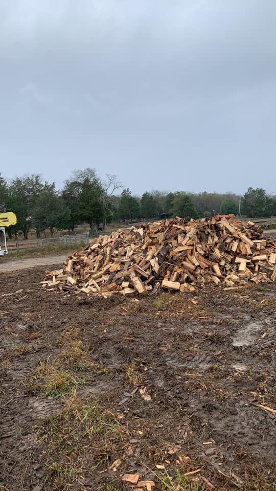 Pile of chopped wood in a muddy field under a cloudy sky