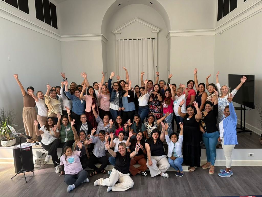 montessori community group raising hands in large indoor gathering