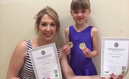 smiling little girl with 2 medals and certificates
