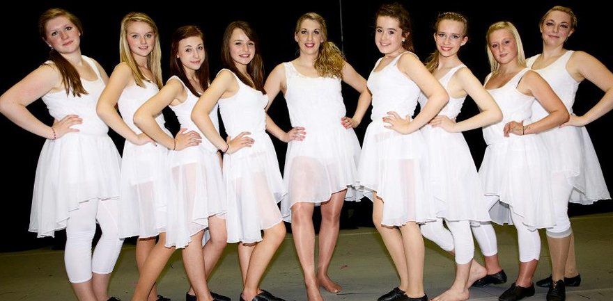 group photo of dancers in white leotards and skirts