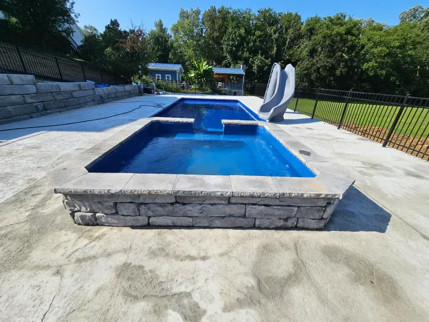 A large swimming pool with a slide in the backyard