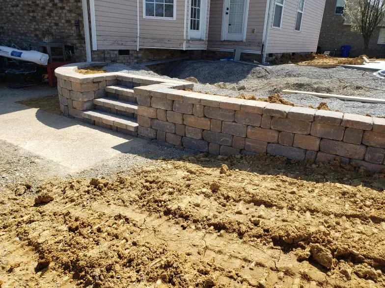 A brick wall with stairs is being built in front of a house.