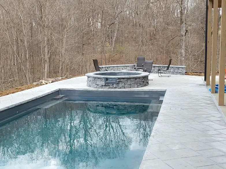 A large swimming pool with a fire pit in the middle of it.