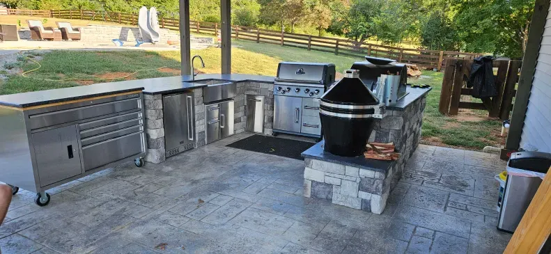 A large outdoor kitchen with stainless steel appliances and a grill.