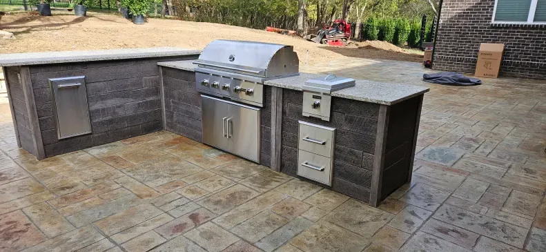 A large outdoor kitchen with a grill and a sink.