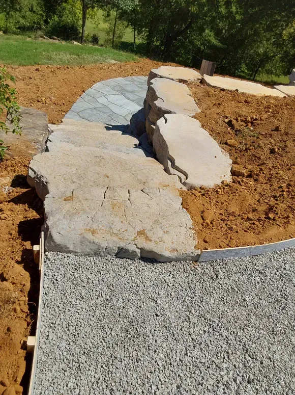 A stone walkway is being built in a backyard