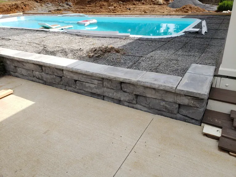 A swimming pool is being built next to a stone wall.