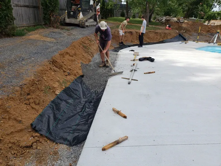 A man is raking gravel on a concrete surface