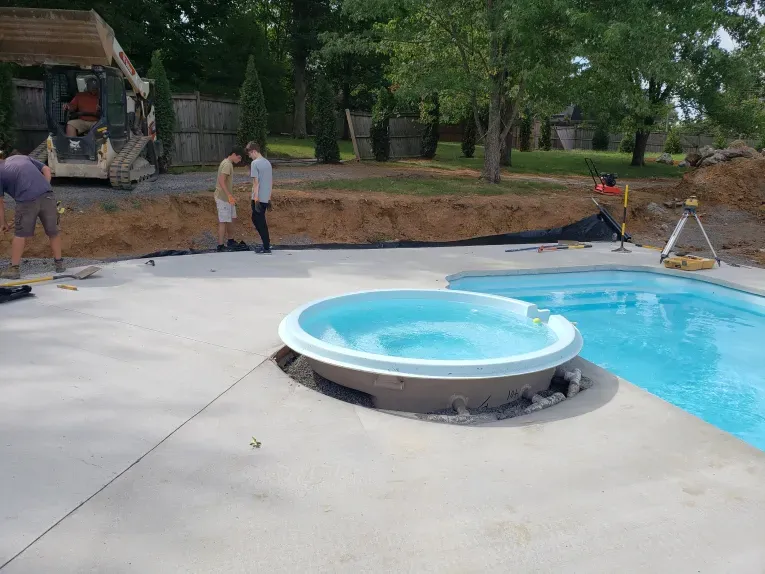 A swimming pool with a hot tub in the middle of it