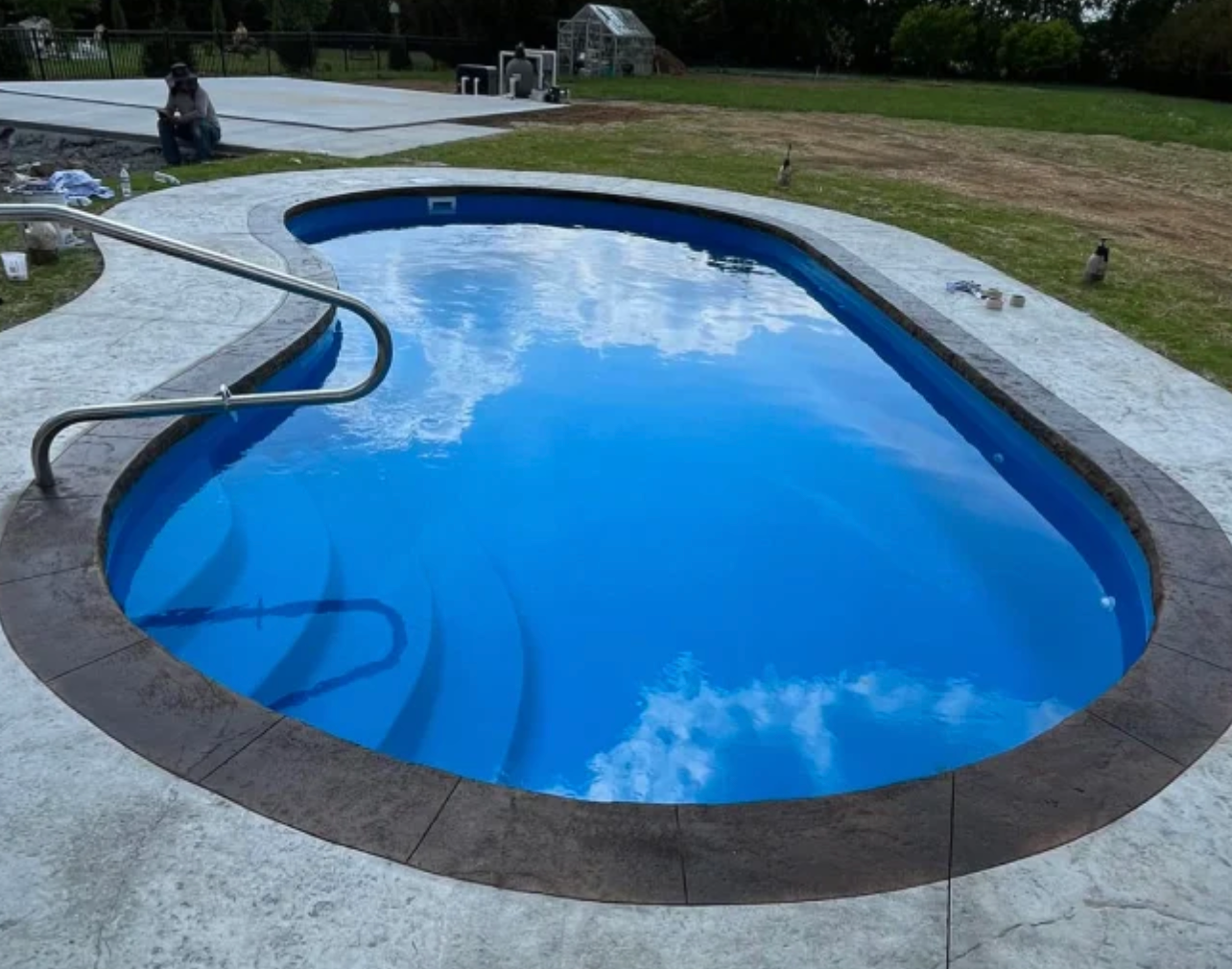 A large swimming pool with blue water and a concrete border