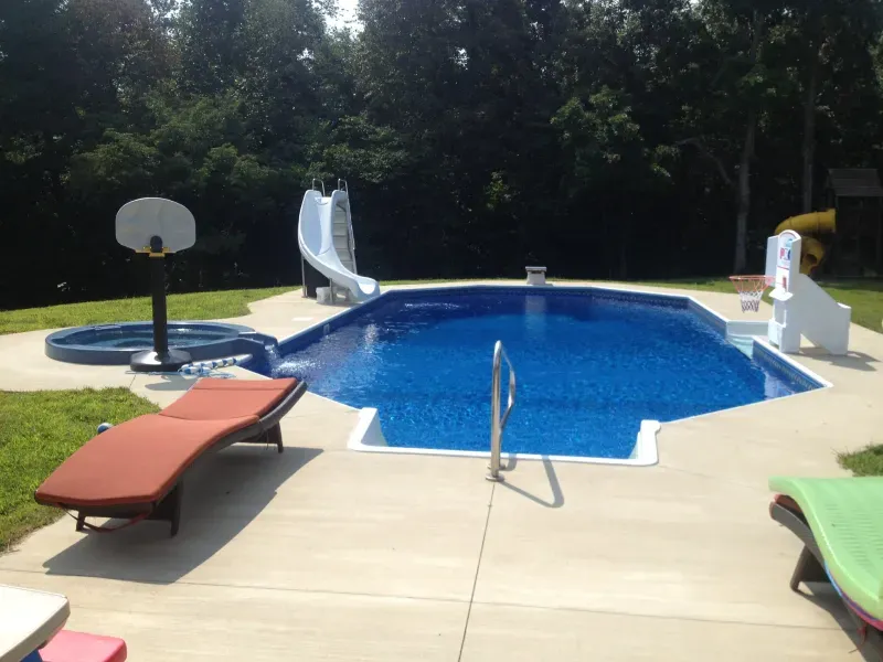 A swimming pool with a slide and a basketball hoop