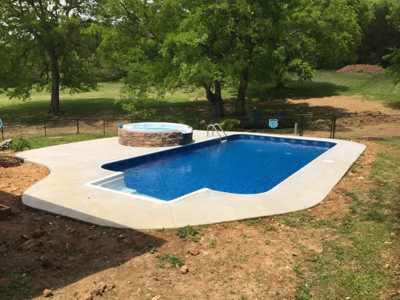 A large swimming pool with a hot tub in the backyard.