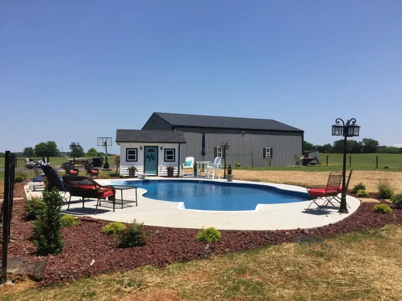 There is a large swimming pool in the backyard of a house.