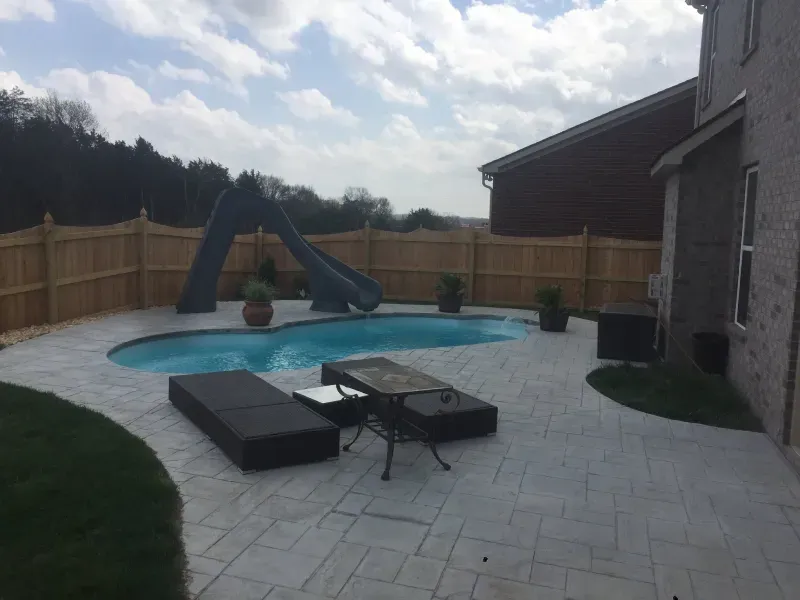 A large swimming pool with a slide in the backyard of a house.