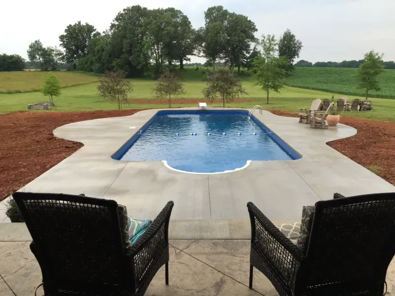 Two chairs are sitting in front of a large swimming pool