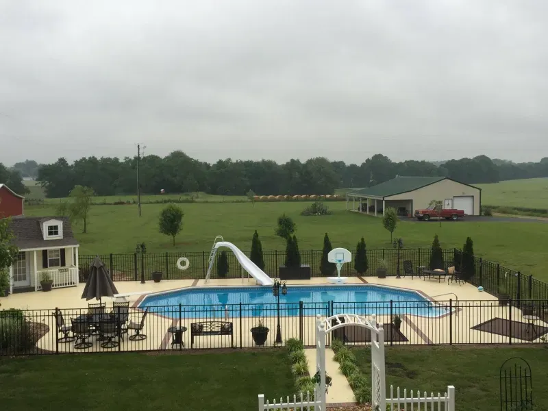 A large swimming pool surrounded by a fence in a backyard.