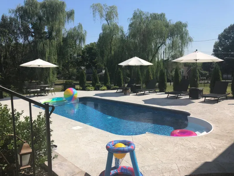 A large swimming pool with umbrellas and chairs around it