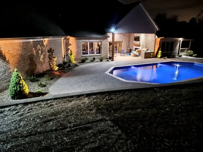 A house with a swimming pool in front of it at night