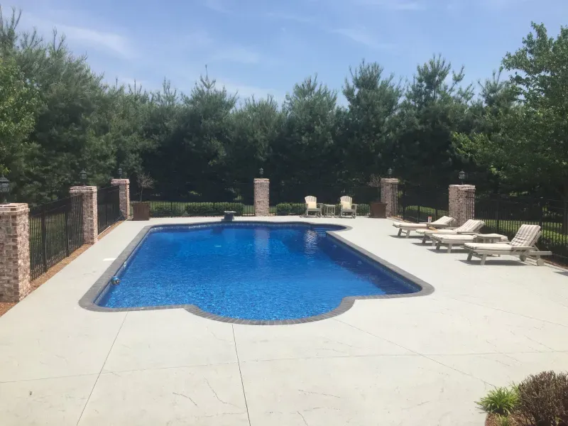 A large swimming pool surrounded by chairs and trees