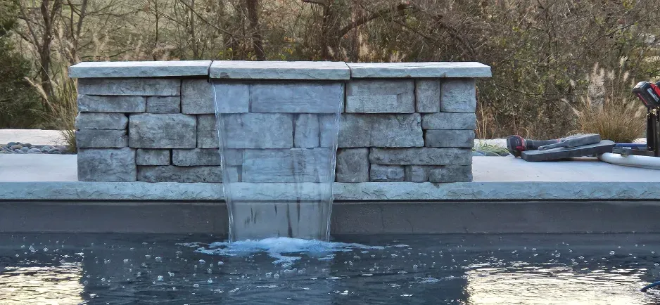 There is a waterfall in the middle of a pool.