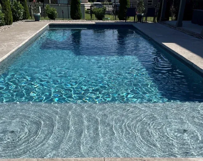 A large swimming pool filled with blue water in a backyard.