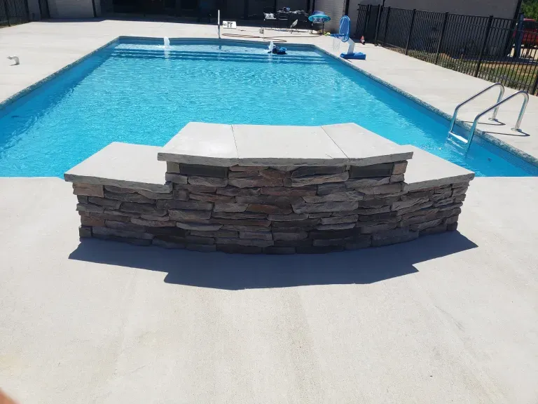 A large swimming pool with a stone wall surrounding it