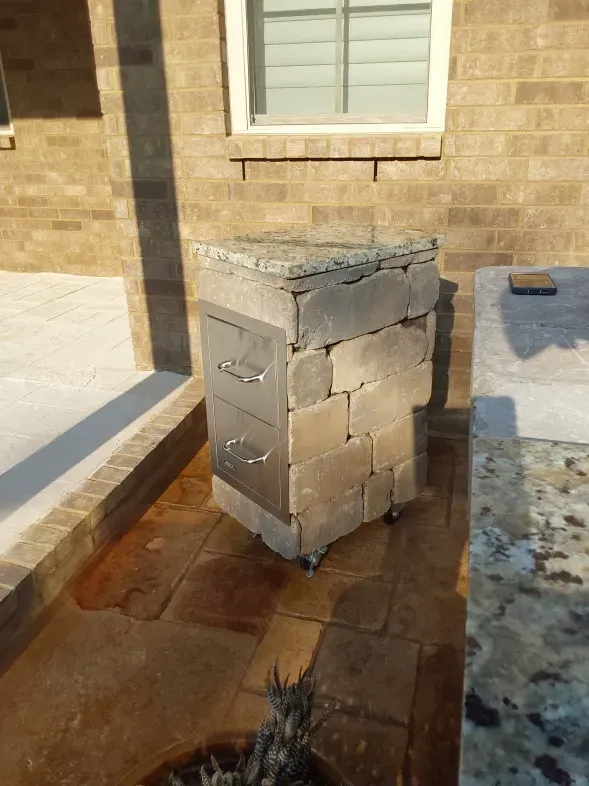 A brick box with drawers is sitting in front of a brick building.