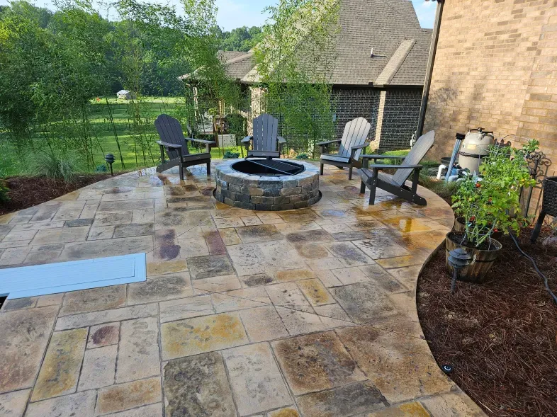 A patio with a fire pit and chairs in front of a house.