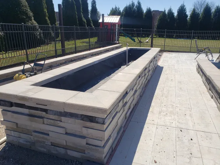 A large brick wall is being built in a backyard