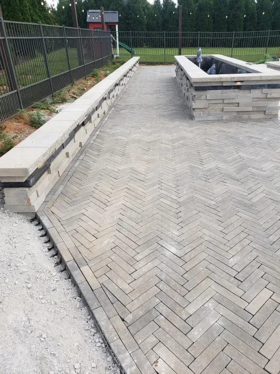A brick walkway with a fence in the background