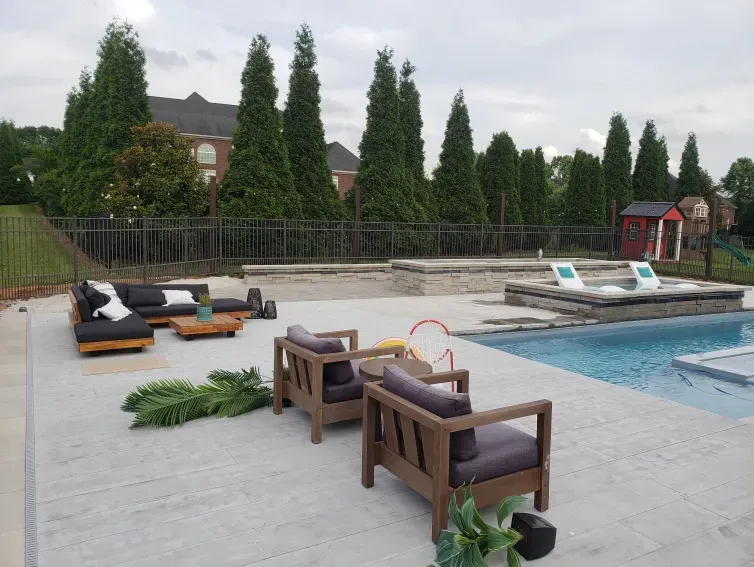 A patio with chairs and a couch next to a pool