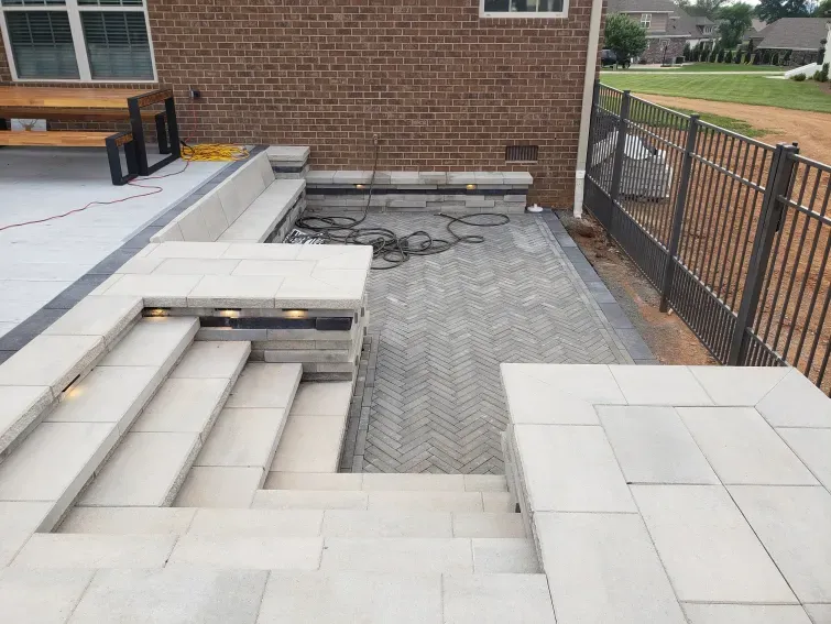 A patio with stairs and a bench in front of a brick building.