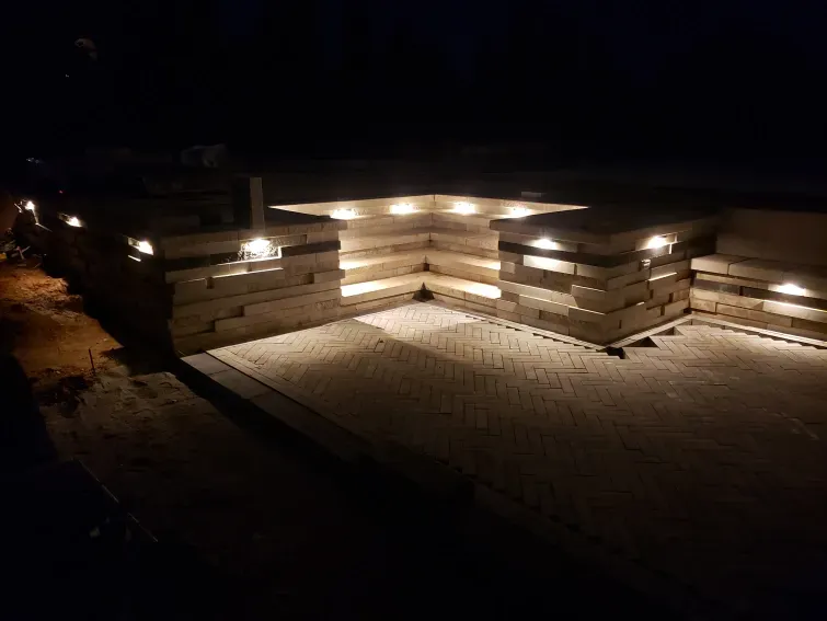 A brick wall with lights on it is lit up at night.