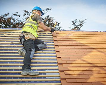 a man is working on the roof of a house .