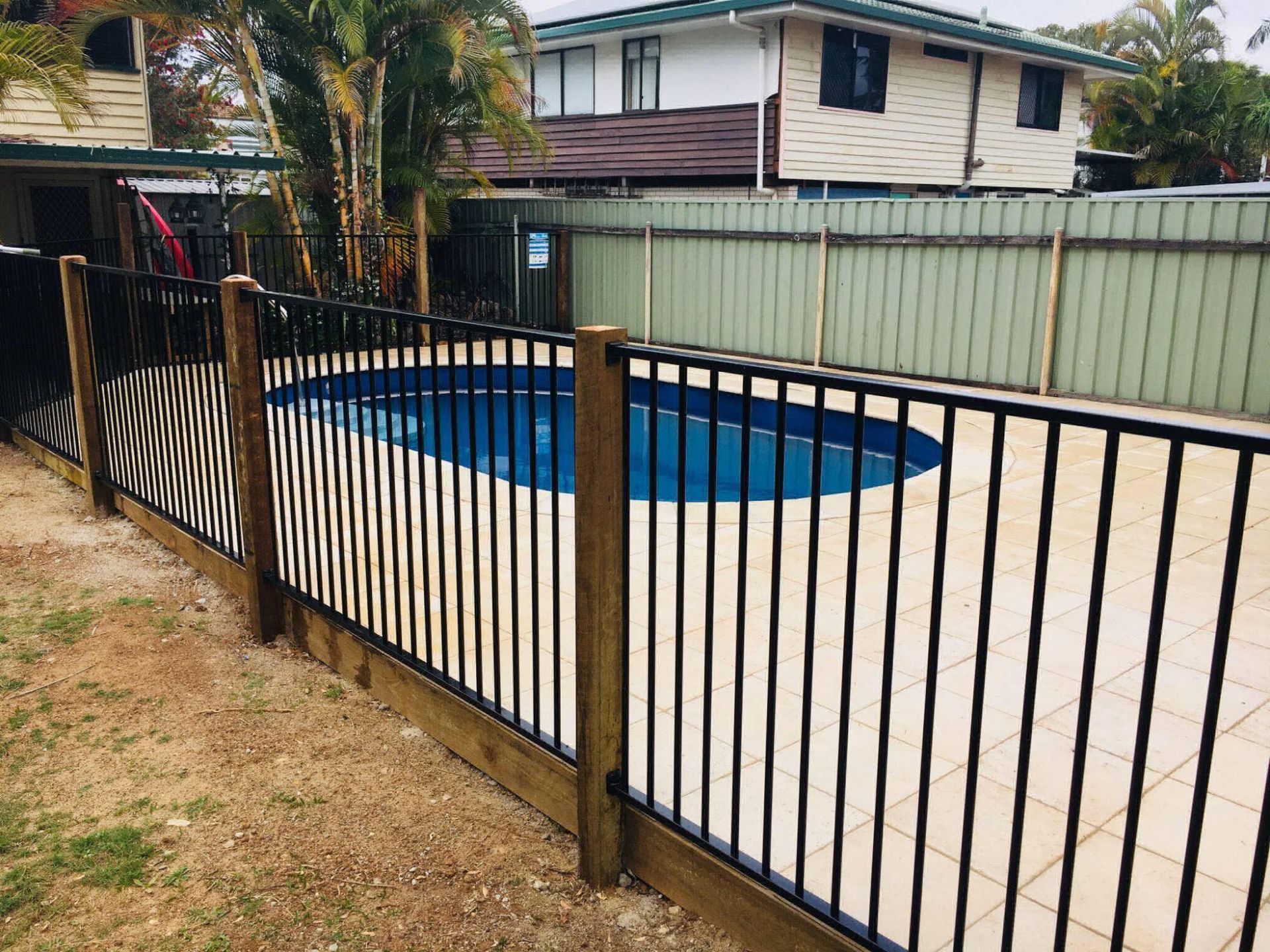 A fence surrounds a swimming pool in front of a house.