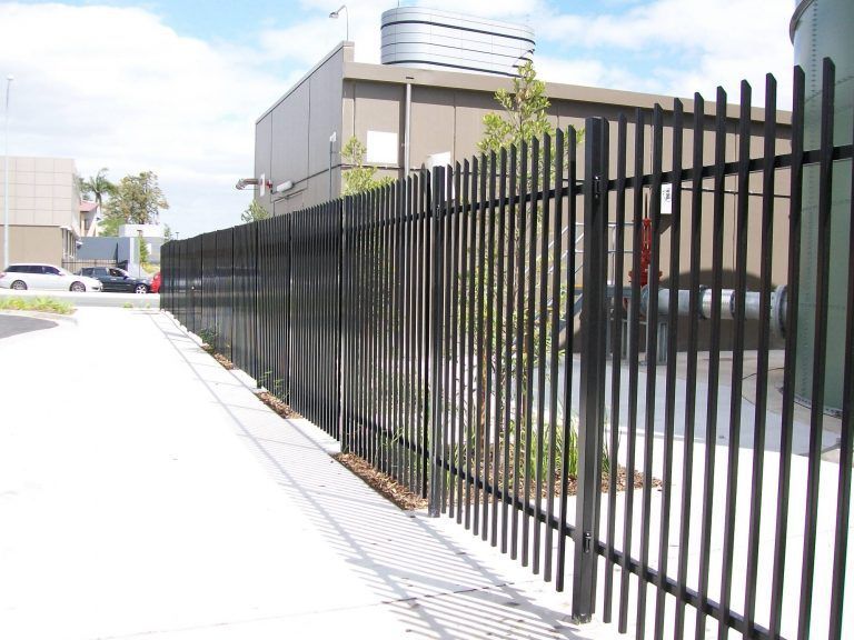 A black metal fence along a sidewalk in front of a building