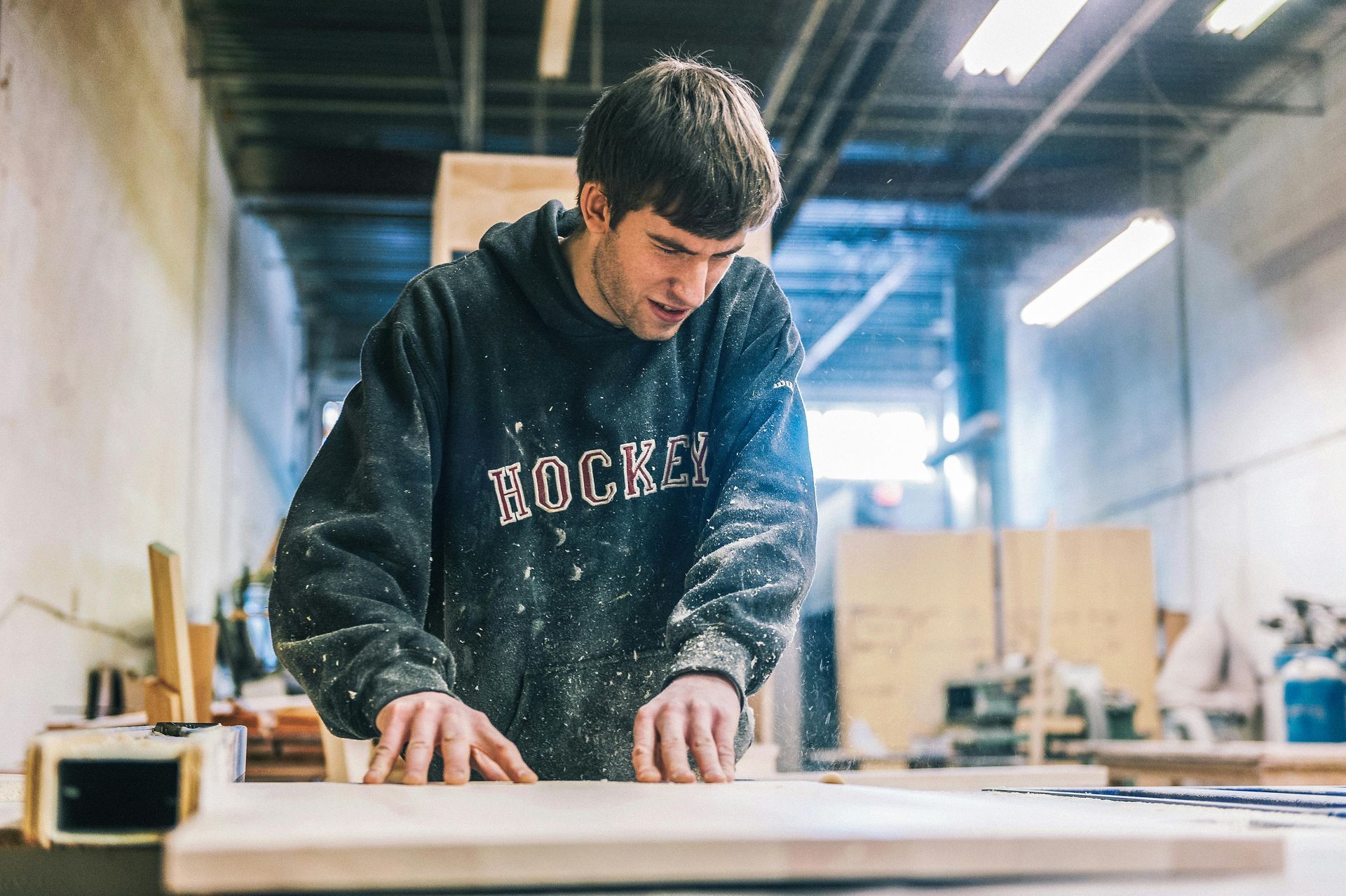 A man is working on a piece of wood in a workshop.