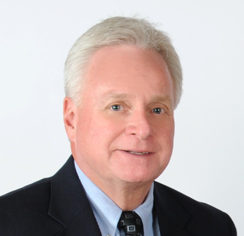 A man in a suit and tie is smiling for the camera