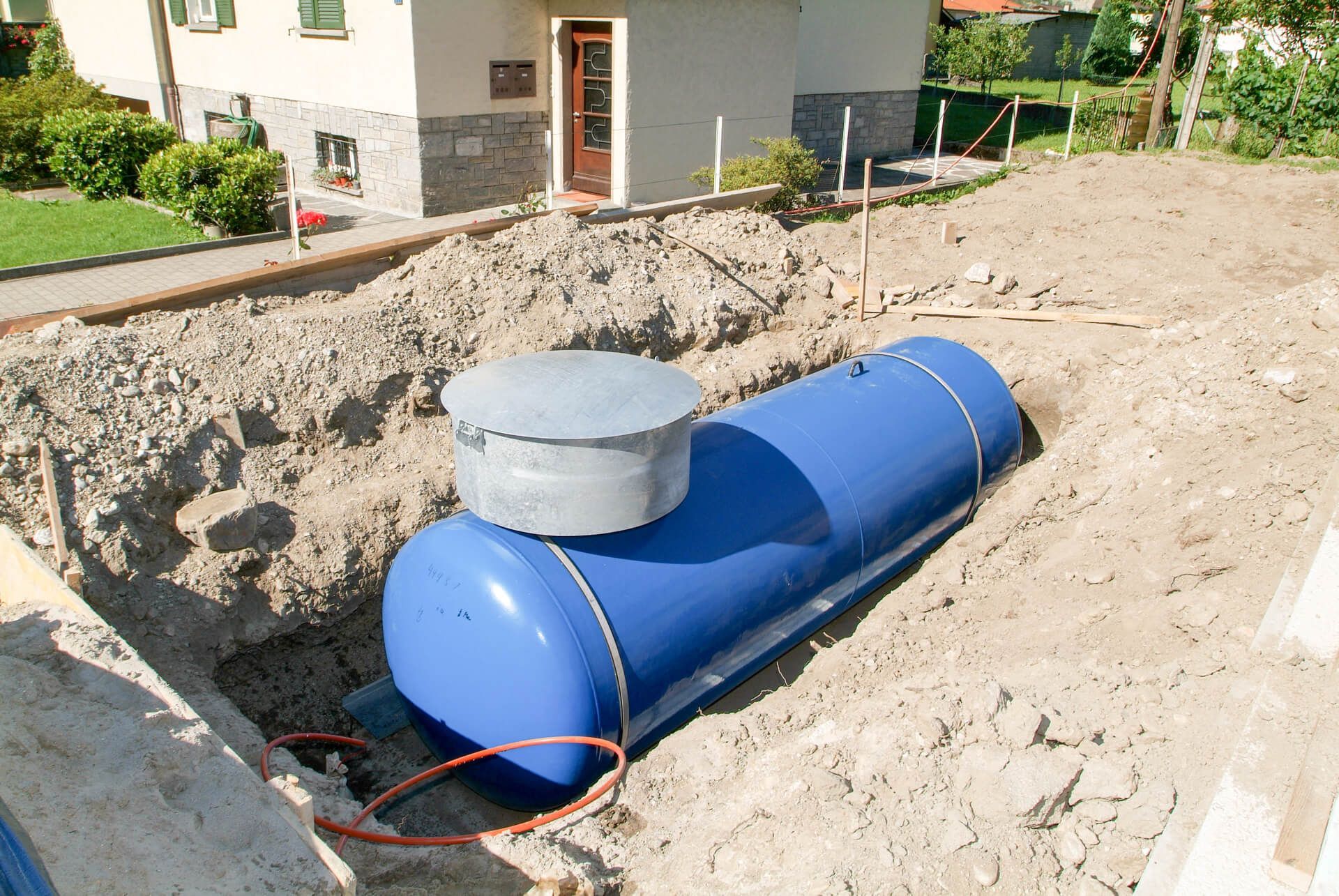 A Blue Tank in The Dirt in Front of A House