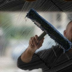 A man is cleaning a window with a mop.