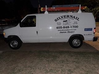 White Silvernail service van with ladder on top parked at night.