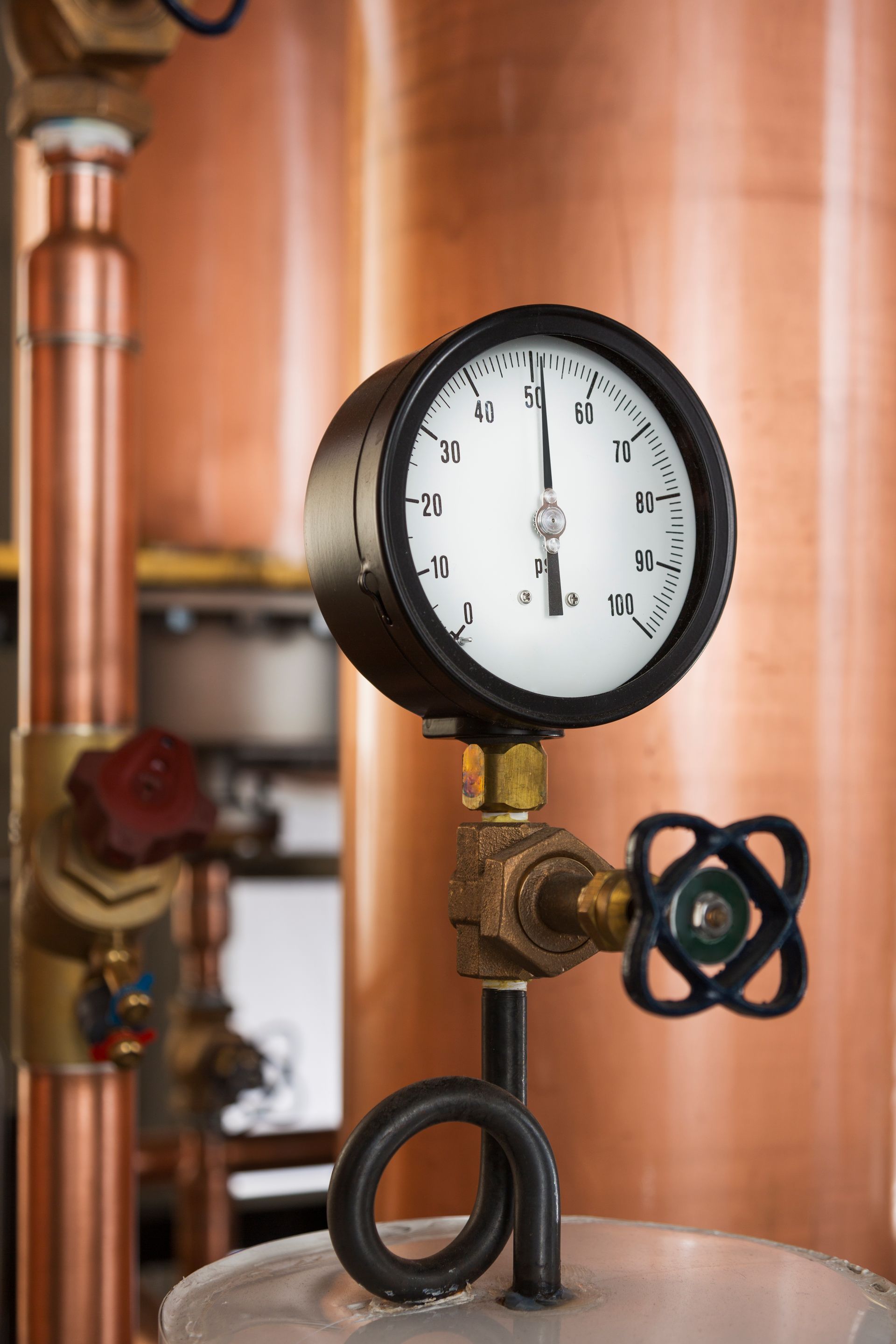 Pressure gauge attached to copper pipes and tank, showing a mid-range reading.