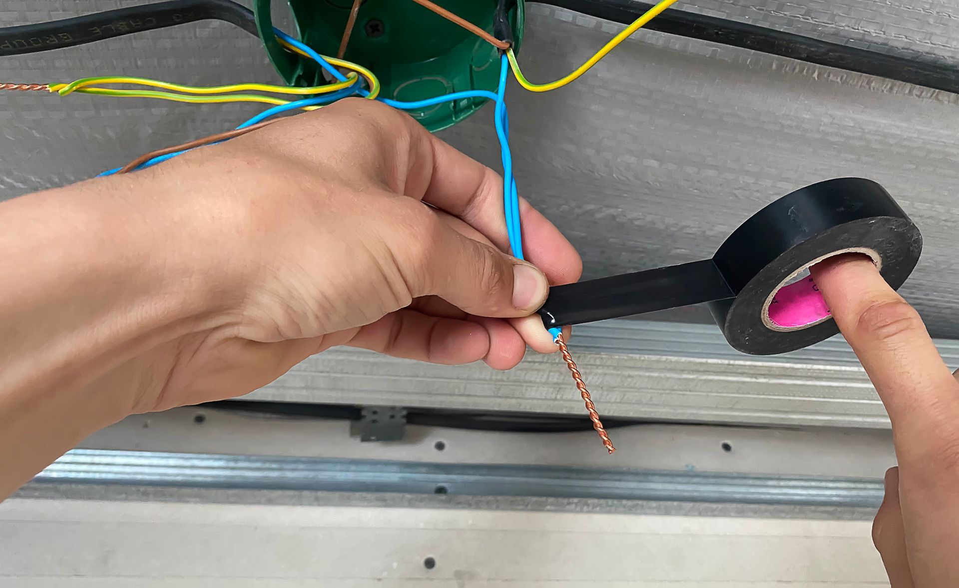 Person taping electrical wires with black tape.