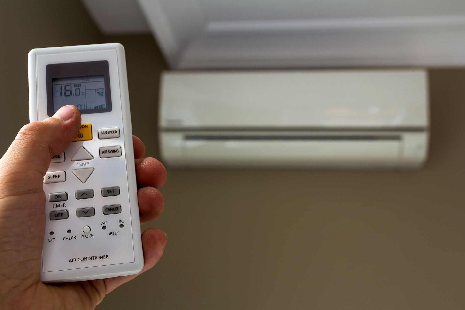 Hand holding remote, adjusting air conditioner set to 16 degrees.