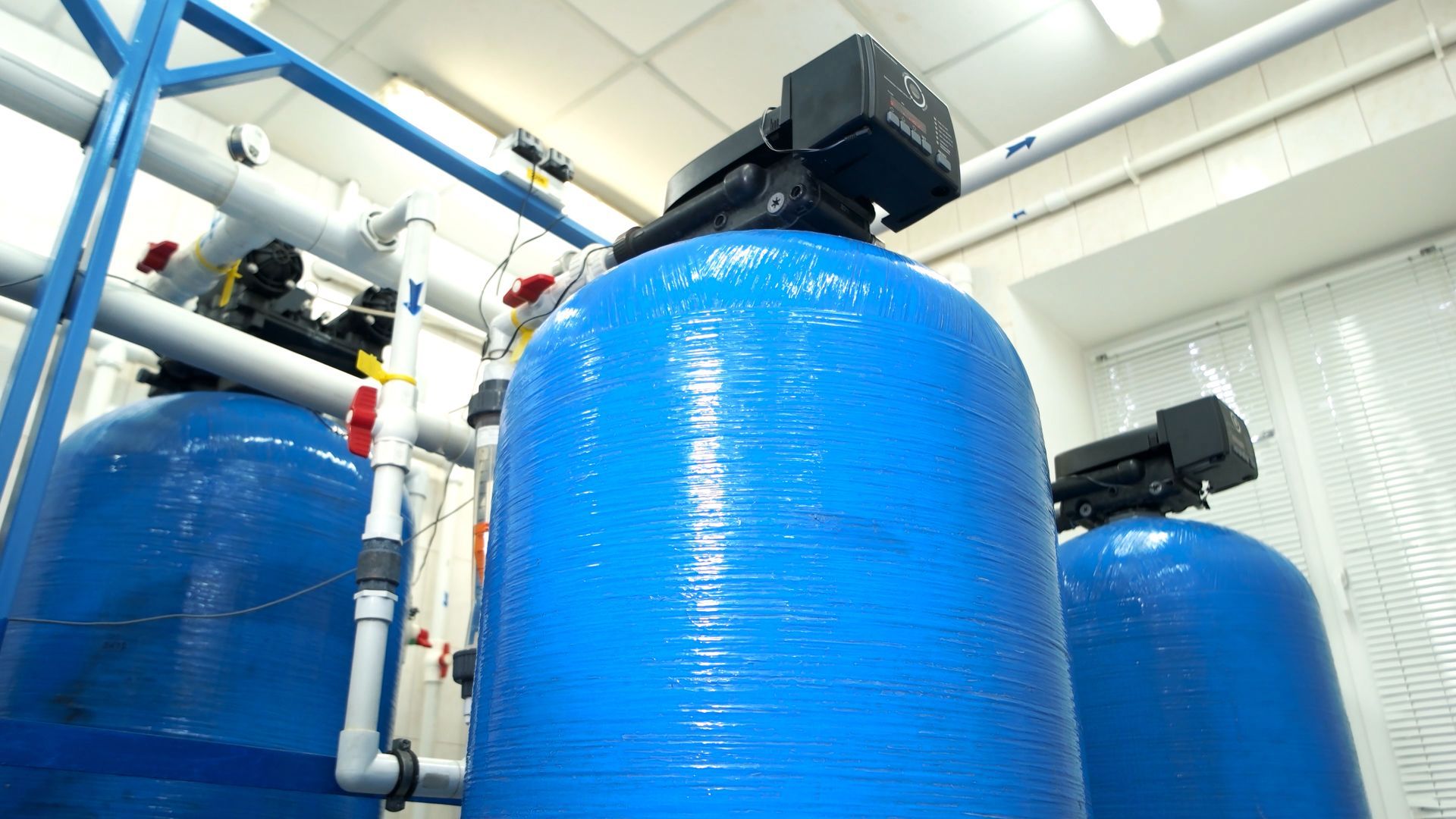 Blue water filtration tanks in an industrial setting, with pipes and equipment.