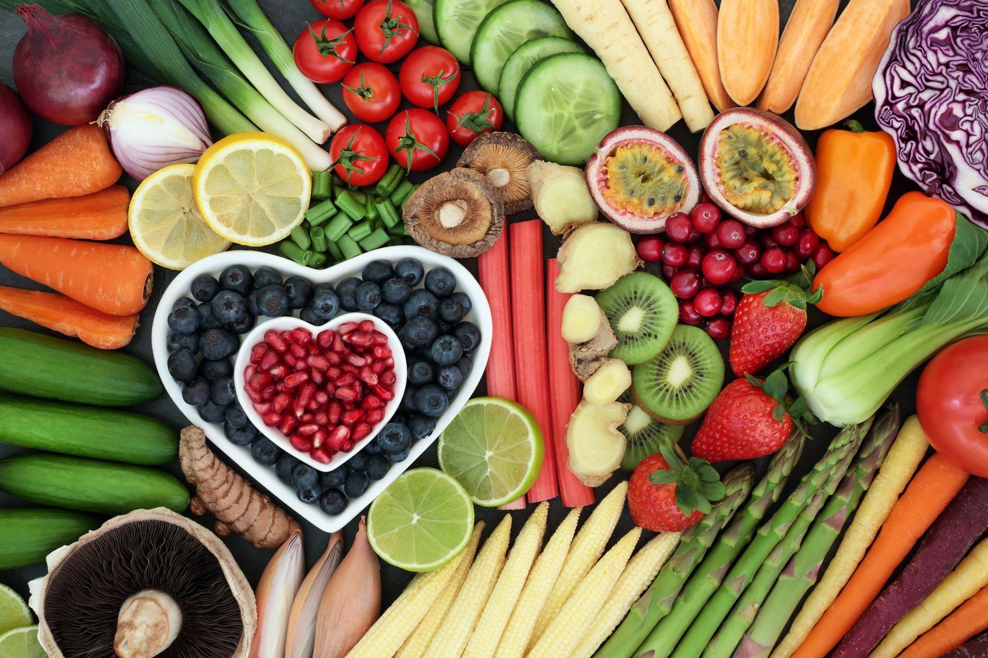 A variety of fruits and vegetables are arranged in a heart shape.
