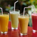 A group of smoothies with straws on a table.