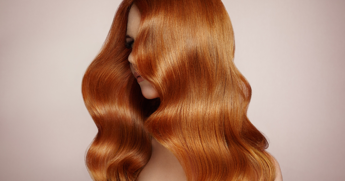 A woman with long red hair is wearing a wig.