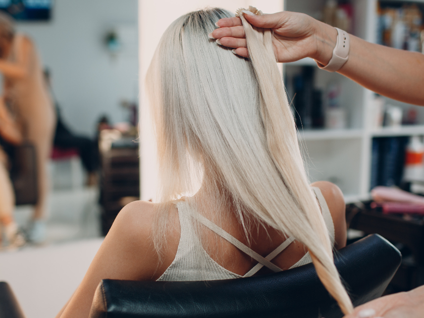 A woman is getting her hair done by a hairdresser in a salon.