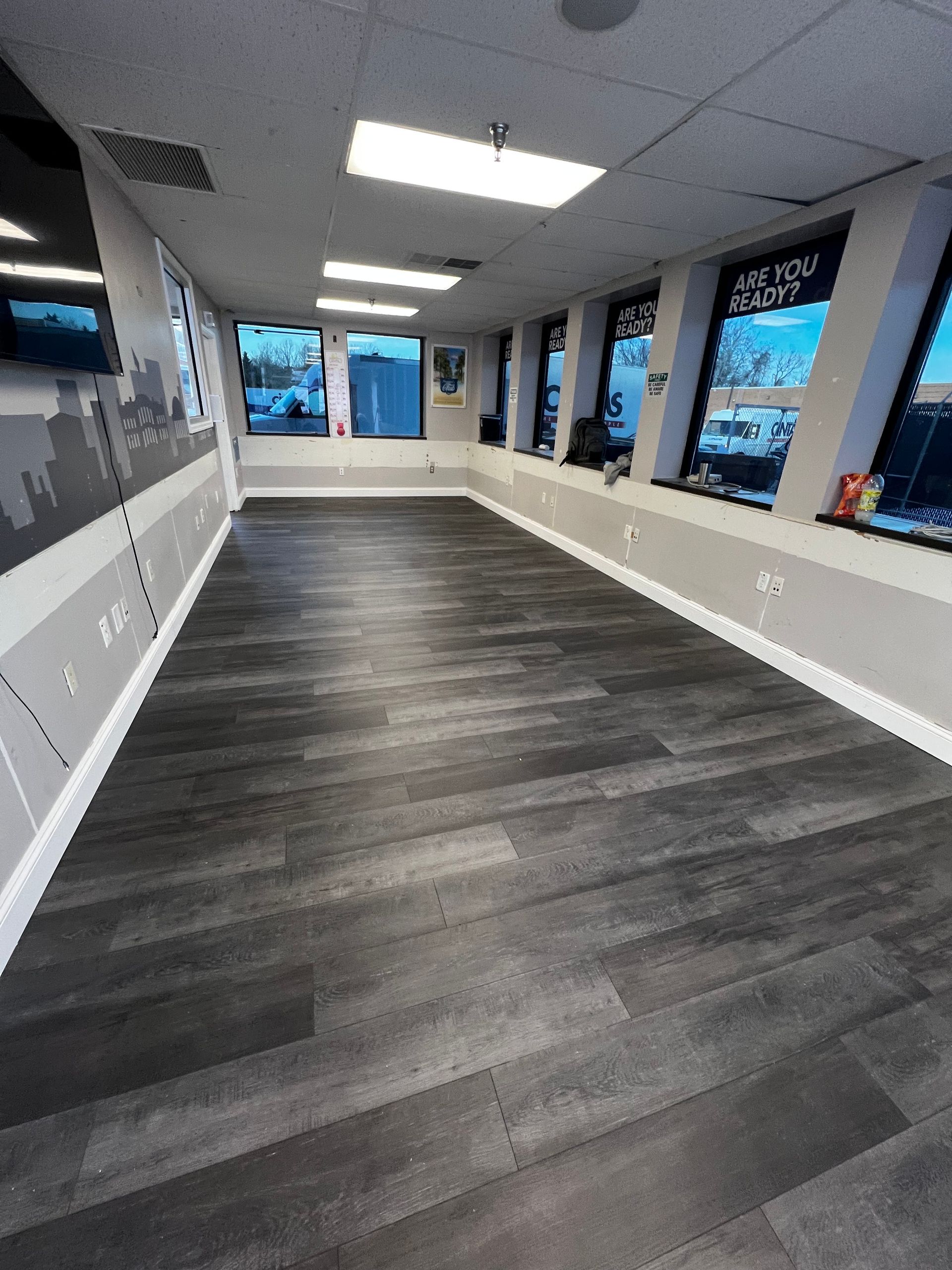 A large room with a wooden floor and lots of windows